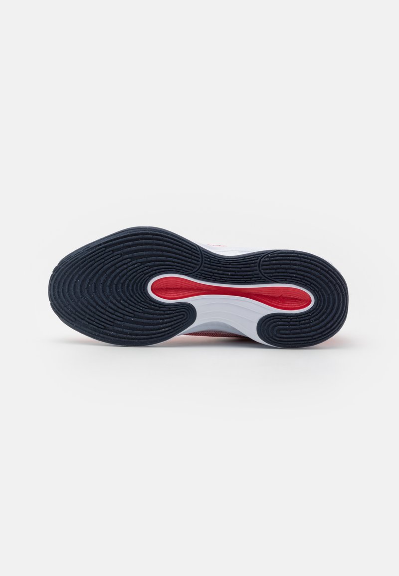 Podeszwa sportowego buta z czarnym gumowym materiałem o teksturowanym wzorze, białą amortyzującą częścią środkową z czerwonymi akcentami oraz widocznym detalem logo.