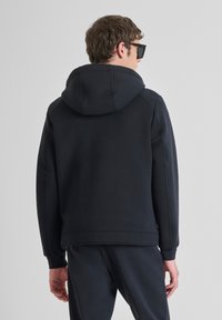 Donkerblauwe hoodie met een trekkoordkap, ribgebreide manchetten en zoom. Gemaakt van zacht fleece-materiaal, met een casual pasvorm en een minimalistisch ontwerp.