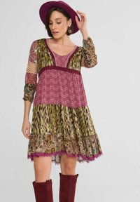 Boho sukienka z patchworkowym wzorem w zielonej, burgundowej i brązowej kolorystyce. Długie rękawy, dekolt w serek i koronkowe wykończenie na dole.