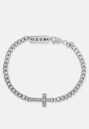 Stříbrný náramek s řetízkem se křížem zdobeným průhlednými krystaly a obdélníkovou destičkou s nápisem "ICON." Zapínání na zacvaknutí.