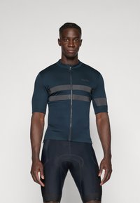 Maillot de cyclisme bleu à manches courtes avec une fermeture éclair à l'avant, arborant des rayures horizontales noires et un design ajusté. Porté avec un short de cyclisme noir.