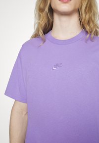 Paarse T-shirt met ronde hals, gemaakt van katoen, met een klein geborduurd Nike-logo op de borst. Korte mouwen en een comfortabele pasvorm.