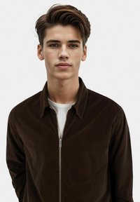 Brown corduroy zip-up jacket with a collar and smooth texture, featuring a metallic zipper and an interior white shirt.