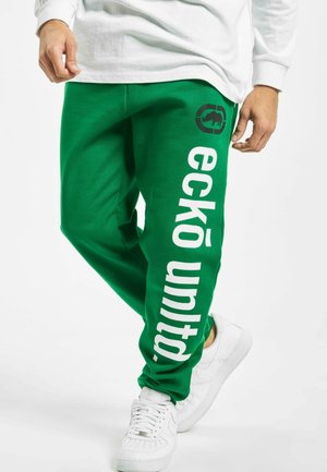 Green sweatpants with white "eckō united" text and logo, featuring a relaxed fit and soft fabric. Worn with white sneakers.