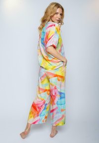 Multicolore, ruime outfit van lichte stof, met een aquarel patroon van gele, roze, oranje en blauwe penseelstreken.