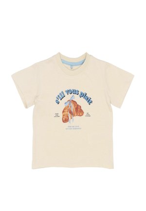 Tricou din bumbac de culoare crem, cu un grafic de croissant, panglică albastră, text albastru și guler rotund cu mâneci scurte.