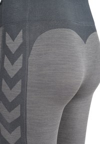 Graue Leggings mit Struktur zeigen ein Zickzackmuster an der Seite, mit einem hohen Bund und einem körpernahem Design, das die Silhouette betont.