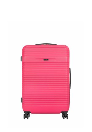 Jasnoróżowa walizka z twardą skorupą o poziomych wypukłościach, czarna rączka u góry oraz cztery czarne obracające się kółka u podstawy.