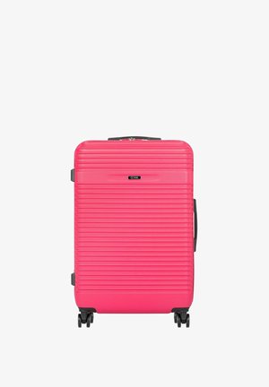 Jasnoróżowa walizka z twardą skorupą o poziomych wypukłościach, czarna rączka u góry oraz cztery czarne obracające się kółka u podstawy.