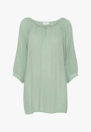 Gaiši zaļš, brīvi piegulošs blūze ar apaļu kakla izgriezumu, trīs ceturtdaļu garuma piedurknēm un r gathered plecu detaļu. Mīksta, teksturēta auduma.