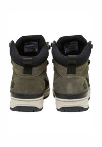 Botas de senderismo de ante verde oscuro con forro de felpa negro, talón reforzado y entresuela de color crema. Presentan tiradores y un detalle del logo.