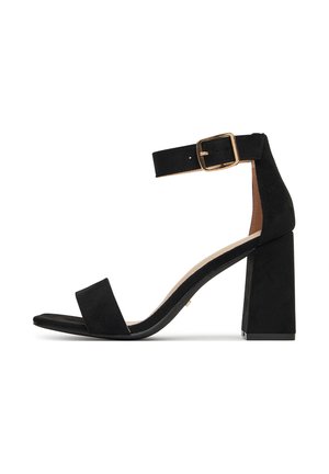 Sandale à talons hauts en daim noir avec une bride à la cheville, une boucle dorée, un bout ouvert et un talon bloc épais pour plus de stabilité.