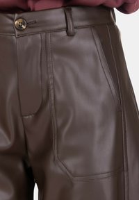 Pantaloni marroni in ecopelle a vita alta con tasche laterali, chiusura con bottoni, passanti per cintura e dettagli di cuciture visibili.