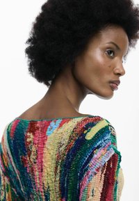 Többszínű, texturált kötött felső széles nyakkivágással, élénk piros, kék, zöld és sárga csíkokkal, redőzött mintával a szöveten.