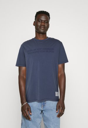 Camiseta de algodón azul marino de manga corta y escote redondo. Presenta una impresión gráfica de texto tonal en la parte frontal y una etiqueta en el dobladillo.