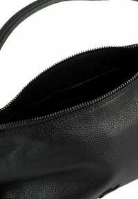 Borsa a tracolla in pelle nera con superficie testurizzata, chiusura con zip e una sola tracolla. L'interno è foderato in tessuto nero e non presenta scomparti aggiuntivi.