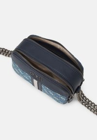 Borsa a tracolla in denim blu e falsa pelle blu navy con catena argentata, doppio scomparto e logo visibile sul davanti.