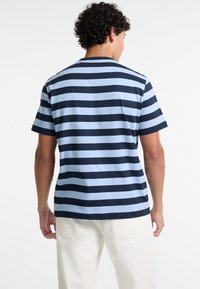 T-shirt col rond à rayures horizontales bleu marine et bleu clair, manches courtes, en coton et avec un ourlet légèrement courbé.