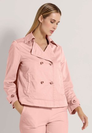 Veste double boutonnage rose clair en tissu lisse avec grand col, deux poches avant et détails de boutons sur les manches.