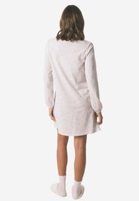 Lys grå langærmet natkjole med prikmønster, lavet af blødt stof, falder over knæet, parret med hvide hjemmesko med bølgede kanter.