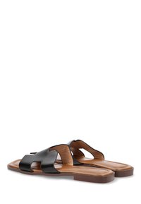 Sandalias de cuero negro con suela plana, que presentan un diseño recortado y plantillas de color marrón. Textura suave con acentos minimalistas.