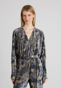 Vestido de manga larga con envoltura en tejido suave y un patrón floral multicolor. Presenta un escote en V profundo y un cinturón a juego en la cintura.