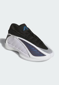 Svarte og hvite treningssko med glatt tekstur, med blå aksenter og en unik, skulpturert design. Strikket overdel og gummisåle.