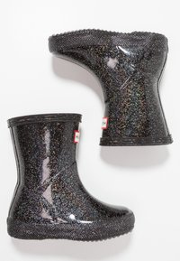 Botas de lluvia negras con purpurina y acabado brillante, suela negra texturizada y acentos en rojo del logo. Diseño corto con puntas redondeadas y forma acampanada.