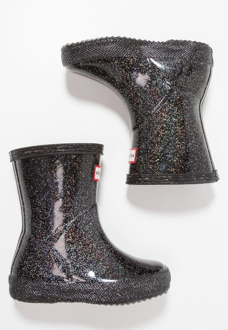 Botas de lluvia negras con purpurina y acabado brillante, suela negra texturizada y acentos en rojo del logo. Diseño corto con puntas redondeadas y forma acampanada.