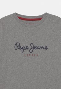 Szary bawełniany t-shirt z okrągłym dekoltem. Na przodzie napis „Pepe Jeans” w ciemnoniebieskim kursywie oraz „LONDON” w bordowym kolorze pod logo.