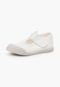 Chaussure en toile blanche pour enfant avec embout en caoutchouc et bride réglable à velcro, vue en angle sur fond blanc.
