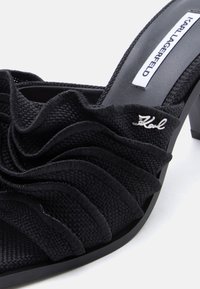 Μαύρο υφασμάτινο mule με ανοιχτή μύτη και τακούνι, με σχεδιασμό από στρώσεις βολάν, μικρό ασημί λογότυπο "Karl" και ετικέτα Karl Lagerfeld στο πέλμα.