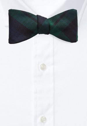 Nœud papillon à carreaux vert foncé et bleu marine sur une chemise blanche à col et boutons.