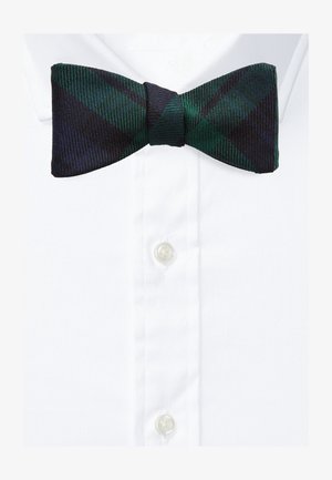 Nœud papillon à carreaux vert foncé et bleu marine sur une chemise blanche à col et boutons.