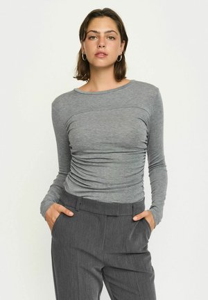 Grijze lange mouw top met een aansluitend ontwerp en gerimpelde textuur bij de taille, gecombineerd met donkergrijze geklede broek.