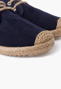Námořnické plátěné espadrilky s tkanými juteovými detaily na špičce a podél podrážky, s hnědými tkaničkami a texturovaným povrchem.