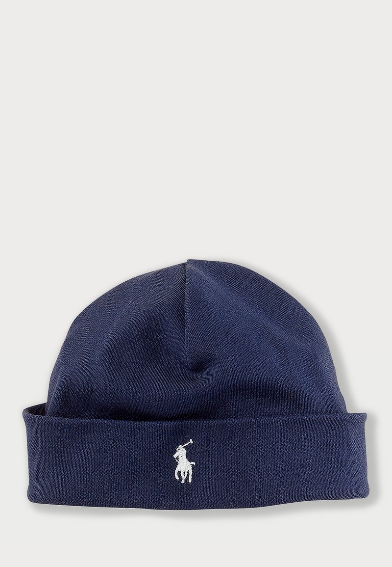 Marineblå strikket lue med brettet kant, laget av mykt materiale. Har en liten hvit brodert logo av en hest og rytter foran.