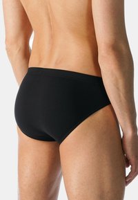 Riveting black cotton slip con un design a vita bassa e una fascia elastica. Texture liscia e dettagli di cucitura minimi, progettato per una vestibilità aderente.