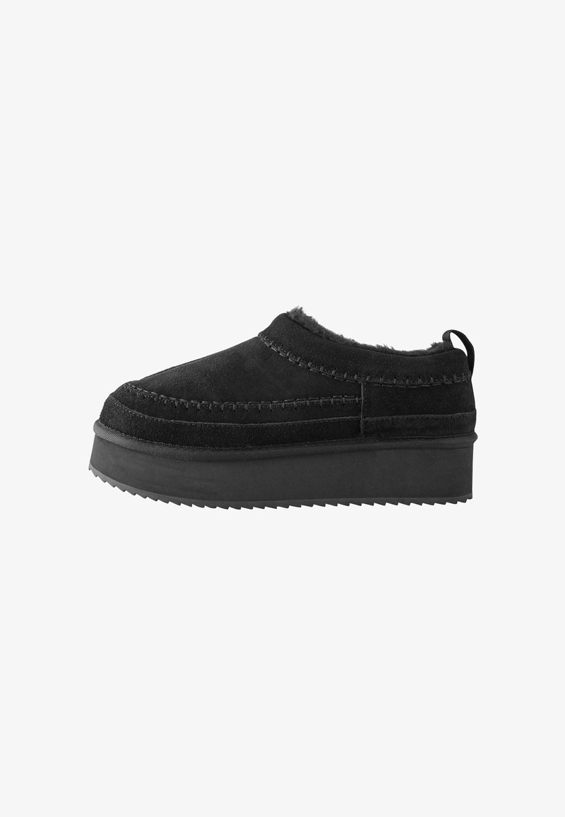 Mustad musta suede'ist kingad, millel on tekstuuriga karvane äär, paks kummitald ja nähtavad õmblusdetailid.