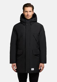 Black puffer coat with a hood, featuring a straight cut, front snap closure, two large patch pockets, and branded label on the bottom.