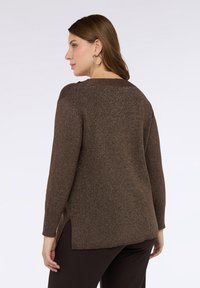 Brauner, strukturierter Pullover mit lockerem Schnitt, langen Ärmeln und seitlichen Schlitzen. Verfügt über einen abgerundeten Ausschnitt und einen dezenten Glitzereffekt im gesamten Material.