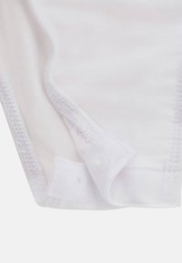 Valkoinen puuvillabodysuit, jossa on napit alareunassa, pehmeä ja sileä pinta sekä viimeistellyt saumat. Upotetut reunat.
