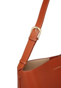 Helle Lederhandtasche mit glatter Textur, ausgestattet mit einer goldfarbenen Schnalle und Nahtakzenten am verstellbaren Tragegurt.