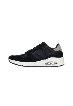 Zapato deportivo negro que presenta una combinación de materiales de ante y nylon, una suela acolchada y una unidad de aire visible en el talón.