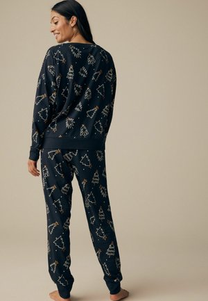 Mörkblå pyjamasset med en tröja med rund halsringning och avsmalnande byxor, dekorerad med mönster av guld- och vitfärgade julgranar och stjärnor. Mjukt tyg.