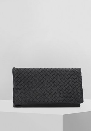 Pochette en cuir tressé noir présentée sur un socle blanc contre un fond gris uni.
