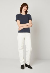 Tums zila īsām piedurknēm T-krekls no mīksta auduma, apvienots ar baltiem taisnām kājām džinsiem un melnu potīšu apavu. Vienkāršs dizains, bez rakstiem.