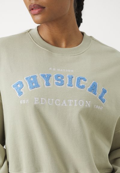 Olive green sweatshirt featuring "PHYSICAL EDUCATION" in blue and white embroidery, ribbed neckline, and soft fabric texture.