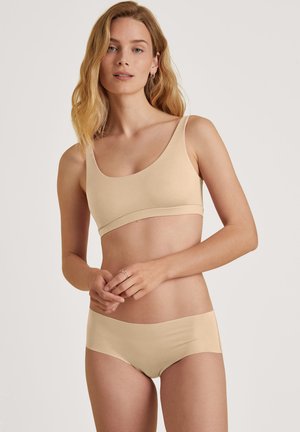 Reggiseno wireless beige senza cuciture e slip coordinati realizzati in un tessuto morbido e elasticizzato, con una superficie liscia e un design semplice.