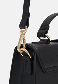 Borsa a tracolla in pelle nera con texture, chiusura a patta, hardware dorato e una tracolla rimovibile con moschettone.